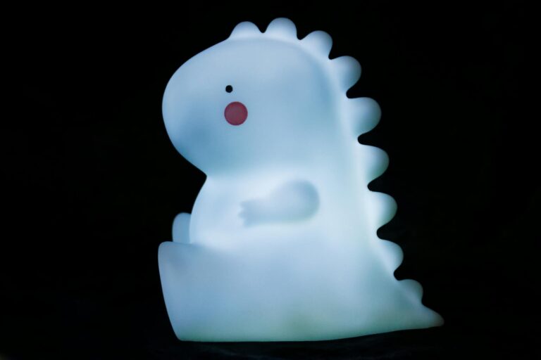 A cute illuminated dinosaur toy sitting against a black background, perfect for a playful and whimsical atmosphere.