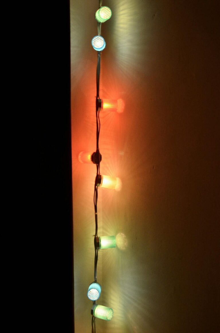 Multicolored Christmas lights with bright illumination on wall in dark room at night